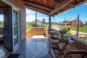 un patio con mesa y sillas y vistas a la calle en Praia Itápiruba 600m - WI-FI 800Mg - 1,5km BR 101 - Espaço comp - Varanda c Pôr do sol, en Imbituba