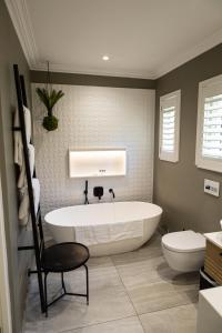 a bathroom with a tub and a toilet and a chair at Cape Village Lodge in Durbanville