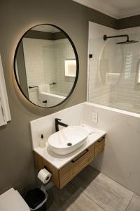 a bathroom with a white sink and a mirror at Cape Village Lodge in Durbanville