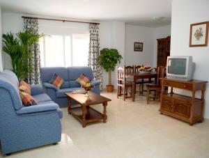 sala de estar con sofá azul y TV en Apartamentos Miguel Angel, en Estepona