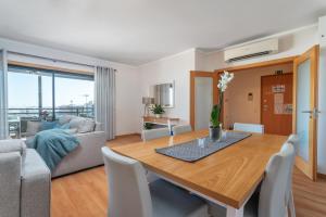 a dining room and living room with a table and chairs at Privilege Apartment Dalia with Rooftop Pool, Village Marina - Olhão in Olhão