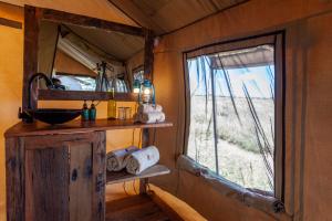 ein Bad mit einem Waschbecken und einem Fenster in einem Zimmer in der Unterkunft Mawe Tented Camp in Serengeti-Savanne