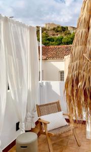 uma varanda com uma cadeira de vime e cortinas brancas em Casita 10 Málaga, holiday home with roof terrace em Málaga