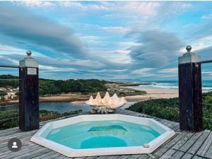 a hot tub on a deck with a view of the ocean at Kennedys Beach Villa in Hermanus