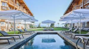 a pool with chairs and umbrellas next to a building at Pirin Golf Villa Compass Property in Bansko