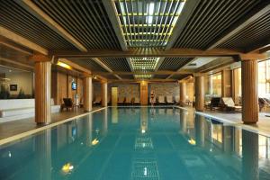 a swimming pool in a hotel with a woman standing in the middle at Pirin Golf Villa Compass Property in Bansko