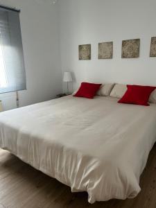 a large white bed with red pillows in a bedroom at La Oliverica in Caudete
