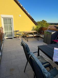 eine Terrasse mit Stühlen, Tischen und einer gelben Wand in der Unterkunft Ferienwohnung Erika in Waischenfeld