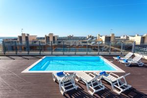 a group of lounge chairs and a swimming pool on a roof at Privilege Apartment Dalia with Rooftop Pool, Village Marina - Olhão in Olhão