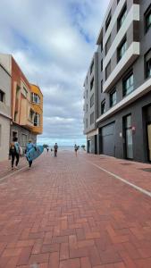 a group of people walking down a street holding surfboards at Gloriamar Las Canteras in Las Palmas de Gran Canaria