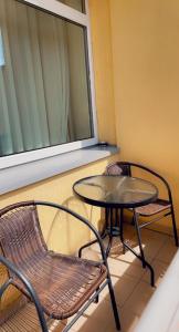 a balcony with a table and a chair and a window at Kornelija in Palanga