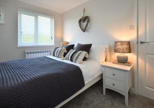 1 dormitorio con 1 cama y 1 mesa con lámpara en Maes Coch, en Abersoch