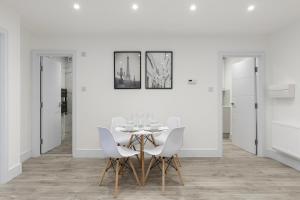 a white dining room with a table and chairs at Star London Vivian Avenue 2-Bed Haven in The Hyde