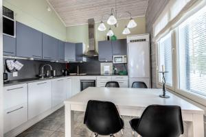 eine Küche mit weißen Schränken sowie einem Tisch und Stühlen in der Unterkunft Holiday Apartment Villa Pisara in Suomutunturi