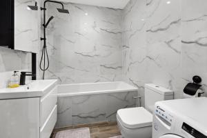 a white bathroom with a toilet and a tub and a sink at Star London Vivian Avenue 2-Bed Retreat with Garden in The Hyde