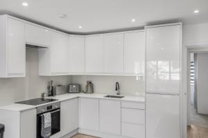 a white kitchen with white cabinets and appliances at Star London Vivian Avenue 2- Bed Abode in The Hyde