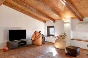 a living room with a flat screen tv and two chairs at Vicolo 10 in Asti