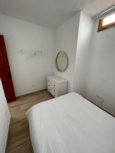 - une chambre blanche avec un lit blanc et un miroir dans l'établissement Casa Mojo, à Agüimes