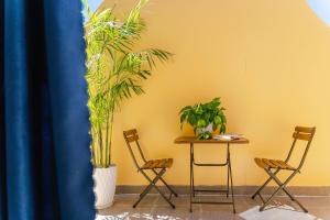 2 chaises et une table avec des plantes sur un mur jaune dans l'établissement AN Boutique Hotel - STAY 24H, à Đà Lạt