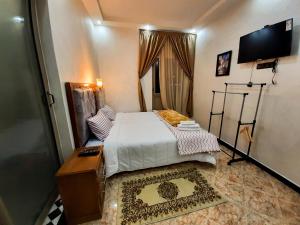 een kleine slaapkamer met een bed en een flatscreen-tv bij DARKOM in Dakhla