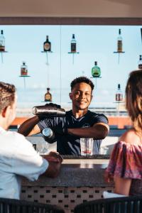 a man standing at a bar with his arms crossed at Elements Hotel & Shops Curaçao in Willemstad