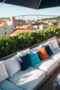 a white couch with colorful pillows on a balcony at Elements Hotel & Shops Curaçao in Willemstad
