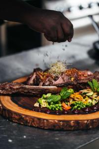 a person sprinkling seasoning on a plate of food at Elements Hotel & Shops Curaçao in Willemstad