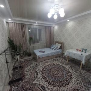 a bedroom with a bed and a table and a rug at Hotel "Тихий Дом Трансфер" in Bishkek
