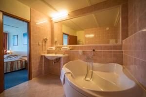 a bathroom with a tub and a sink and a bed at TOP HOTEL Praha in Prague