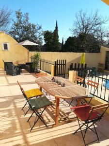 einen Holztisch und Stühle auf einer Terrasse in der Unterkunft Chez TATA in Régusse