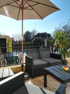 eine Terrasse mit einem Sofa, einem Sonnenschirm und einem Tisch in der Unterkunft Chez TATA in Régusse