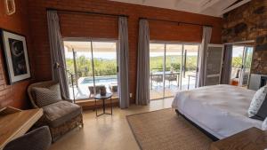 a bedroom with a bed and a balcony at Rockfig Lodge Madikwe in Madikwe Game Reserve +92 photos