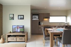 a kitchen and dining room with a table and a television at Villa 2 chambres au bord du lac de l'Eau d'Heure in Froid-Chapelle
