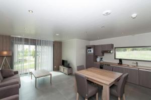 a kitchen and living room with a wooden table at Villa 2 chambres au bord du lac de l'Eau d'Heure in Froid-Chapelle +6 photos
