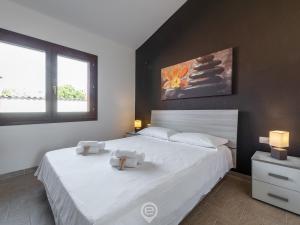 1 dormitorio con 2 camas con sábanas blancas y 2 ventanas en House Anne, en Solinas