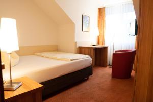 Hotel Jägerhof في باد هيرسفيلد: غرفه فندقيه بسرير ومصباح ونافذه