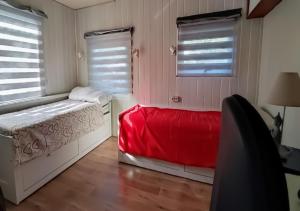 1 dormitorio con cama roja y ventanas en superbe mobil home, climatisé, ss vis a vis, au calme, dans super domaine, en Fréjus