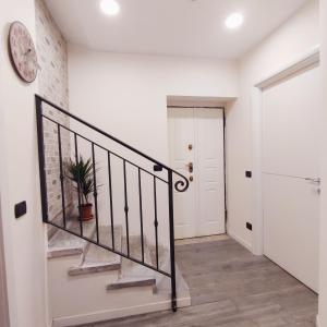 a white hallway with a staircase and a clock on the wall at il Sole di Baggio in Milan