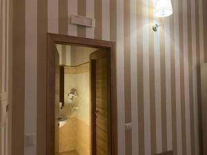 ein Badezimmer mit einer gestreiften Wand und einem Spiegel in der Unterkunft La Valle degli Ulivi in Acquedolci