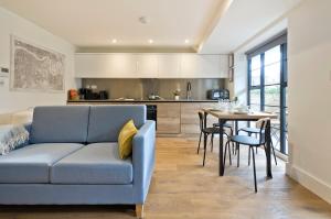 ein Wohnzimmer mit einem blauen Sofa und einem Tisch in der Unterkunft Luxury one bedroom Greenwich studio apartment near Canary Wharf by UnderTheDoormat in London