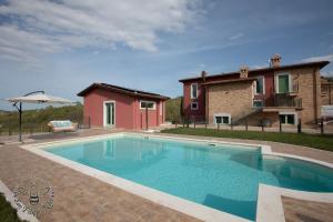 a swimming pool in front of a house at Agriturismo San Filippo Neri in Castignano