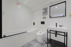 ein weißes Badezimmer mit einer Badewanne und einem Waschbecken in der Unterkunft Luxury one bedroom Greenwich studio apartment near Canary Wharf by UnderTheDoormat in London