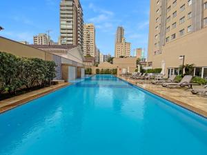 a large blue swimming pool with chairs and buildings at Exuberante hotel na Vila Olimpia in Sao Paulo