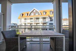 een tafel en stoelen op een balkon met een gebouw bij Home Away, Light and Bright in Cadzand