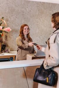 een vrouw geeft een vrouw een mobiele telefoon bij Havendijk Hotel in Schiedam