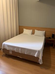 1 cama con sábanas blancas y almohadas en una habitación en Hotel Buriti da Serra, en Itaipava