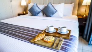 a tray of croissants and coffee cups on a bed at Loumage Suites and Spa in Manama