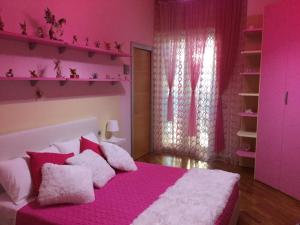 Dormitorio rosa con cama con sábanas y almohadas rosas en B&B La Favola en Castellana Grotte