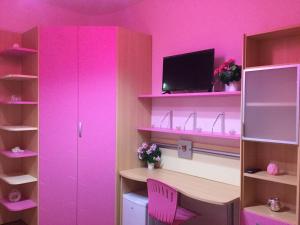 Habitación rosa con escritorio y TV. en B&B La Favola en Castellana Grotte