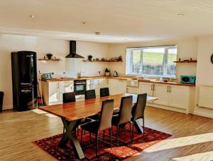 uma grande cozinha com uma mesa de madeira e cadeiras em Country Lodge Retreat em Lydney